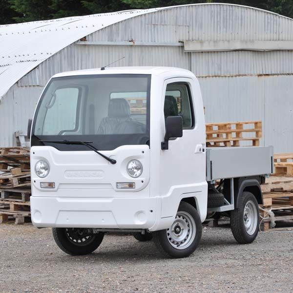 Camionnette utilitaire blanche devant un tas de palettes