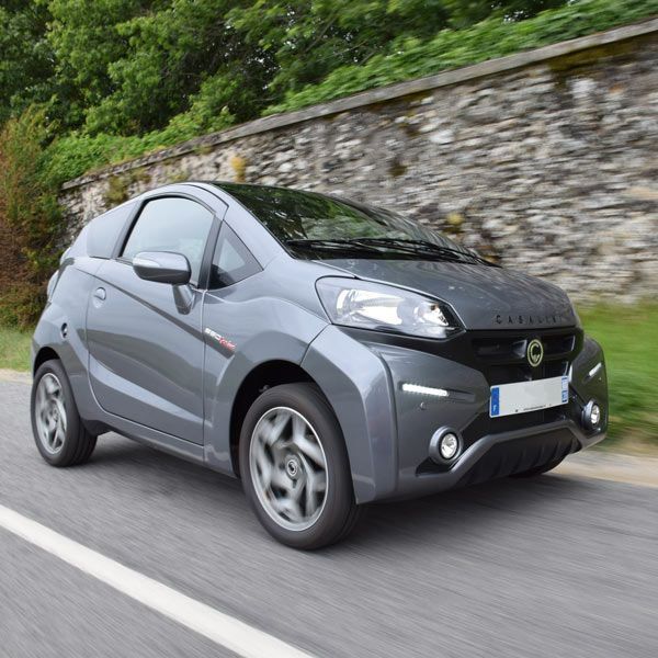 Voiture grise devant un mur en pierre