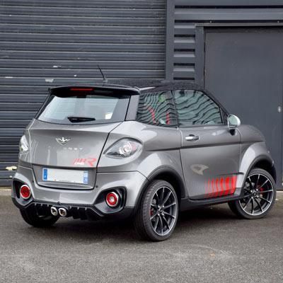 Voiture sans permis de couleur grise devant un mur et un rideau noir