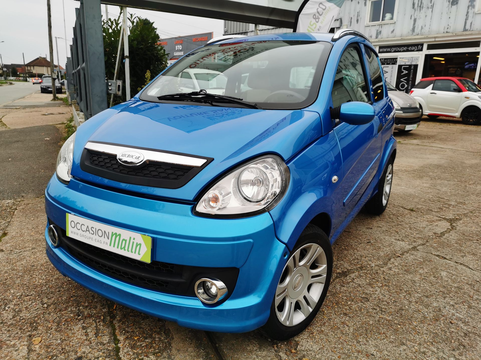 Une voiture sans permis bleue garée devant un bâtiment.