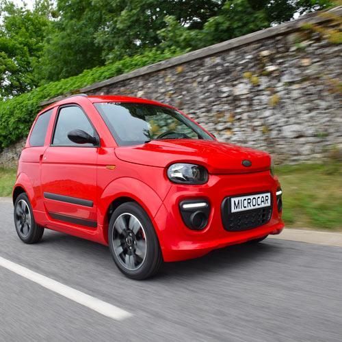 Voiture rouge devant un mur en pierre