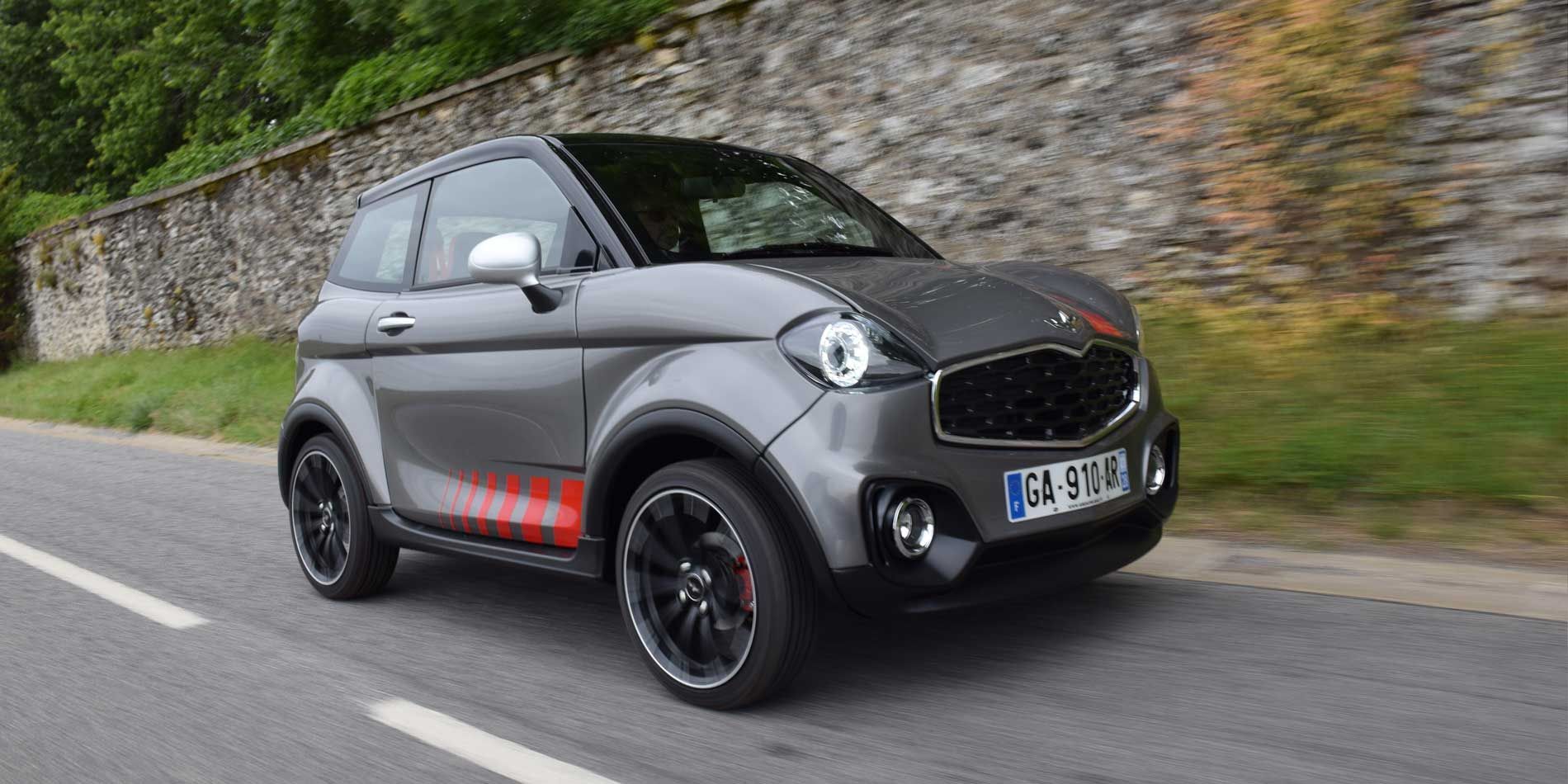 Voiture gris anthracite devant un mur en pierre