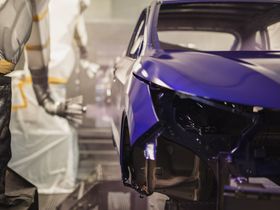 Se está pintando un coche azul en una fábrica.