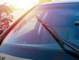 Un primer plano de un parabrisas de automóvil con escobillas limpiaparabrisas.