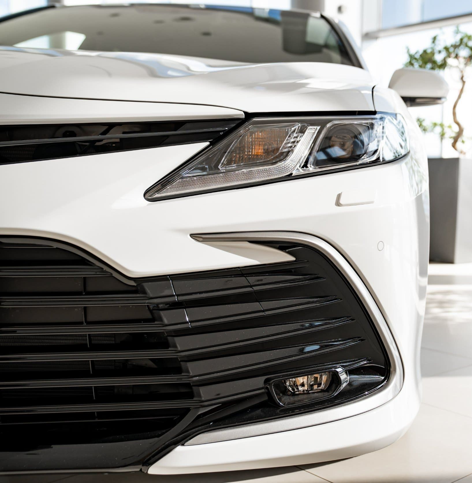 Se muestra el frente de un automóvil blanco en una sala de exposición.