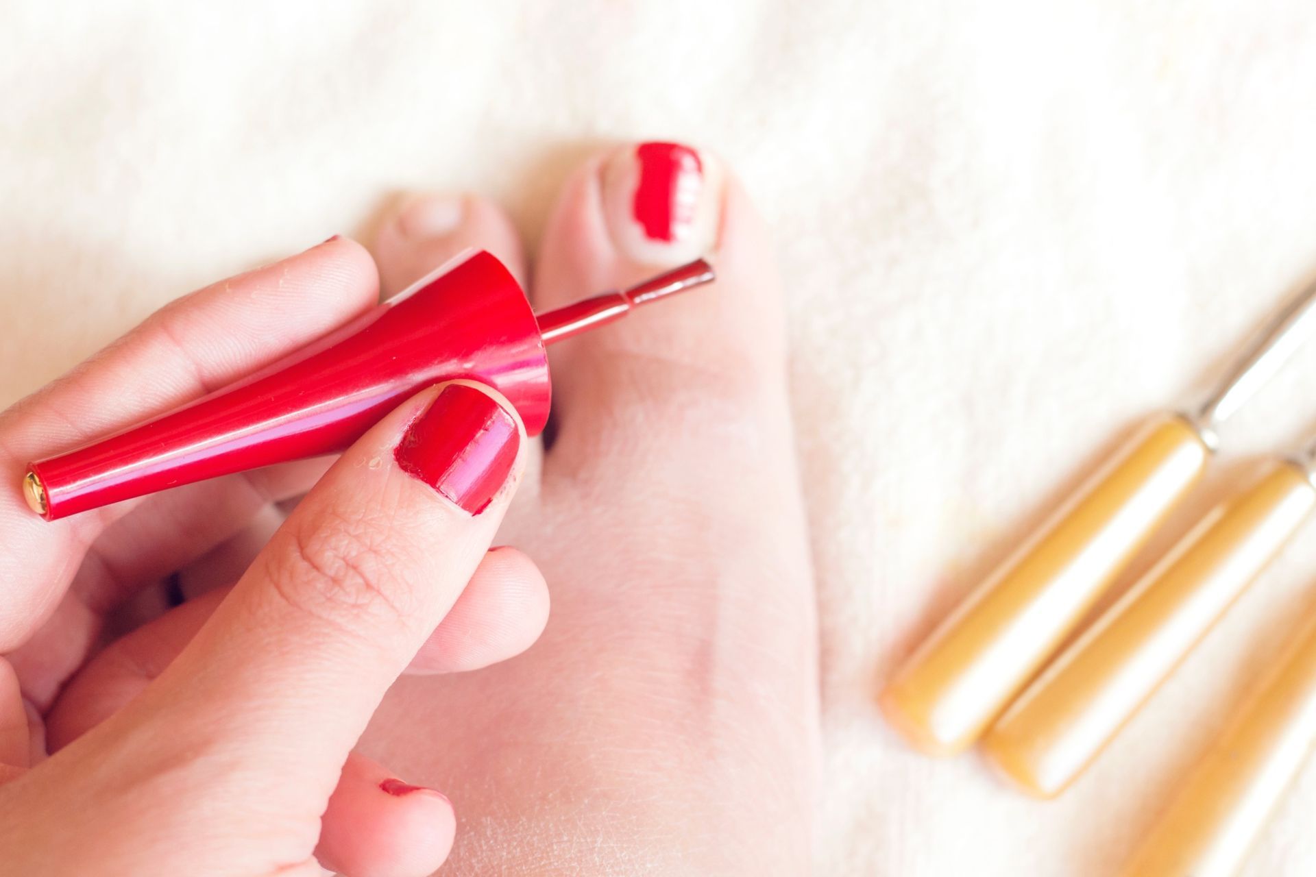 Una mujer se aplica esmalte de uñas rojo en las uñas de los pies.