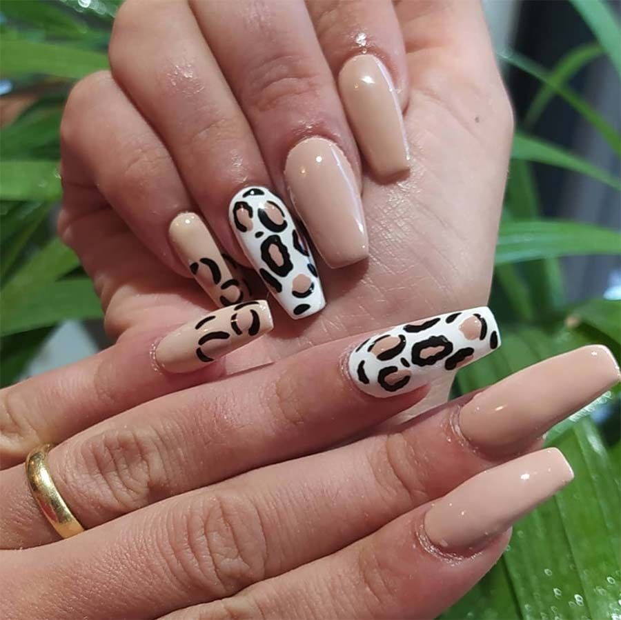 Un primer plano de la mano de una mujer con uñas con estampado de leopardo.