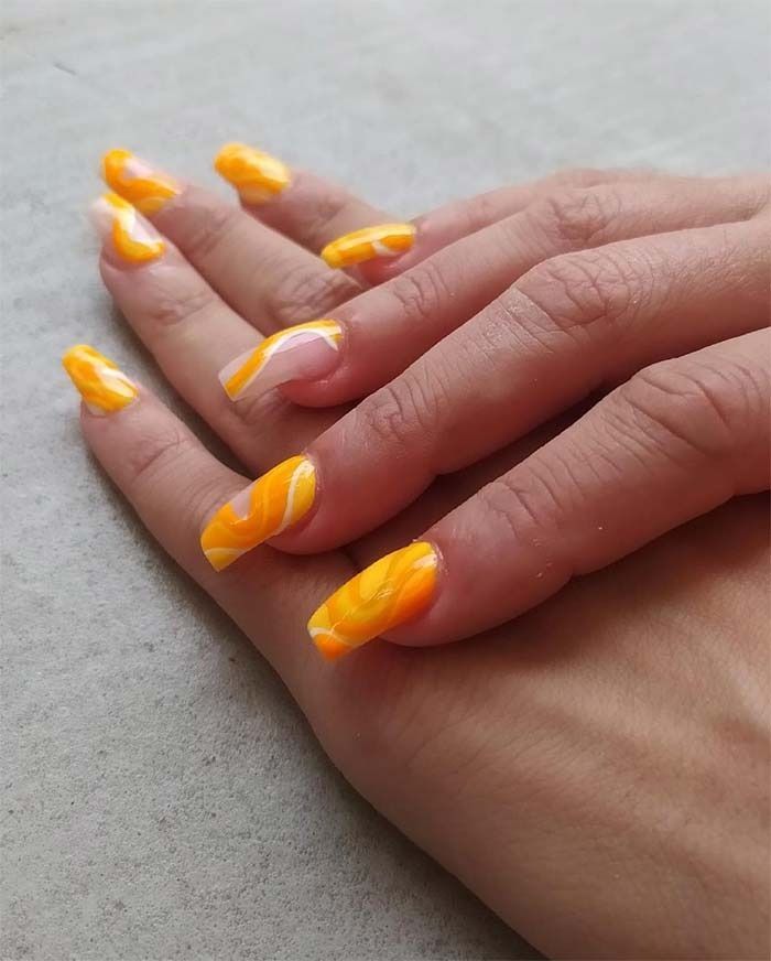 Un primer plano de la mano de una persona con uñas amarillas.