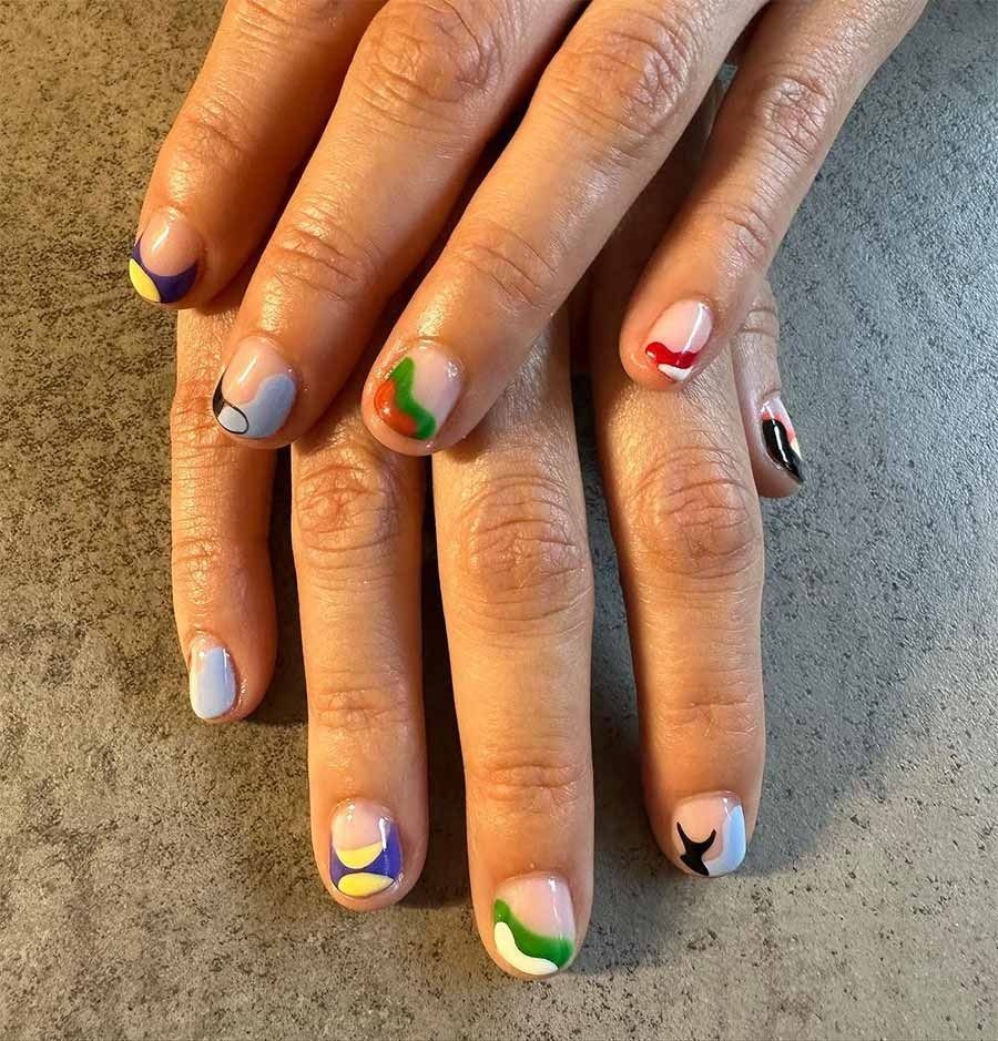 Un primer plano de las uñas de una persona con diferentes diseños en ellas.
