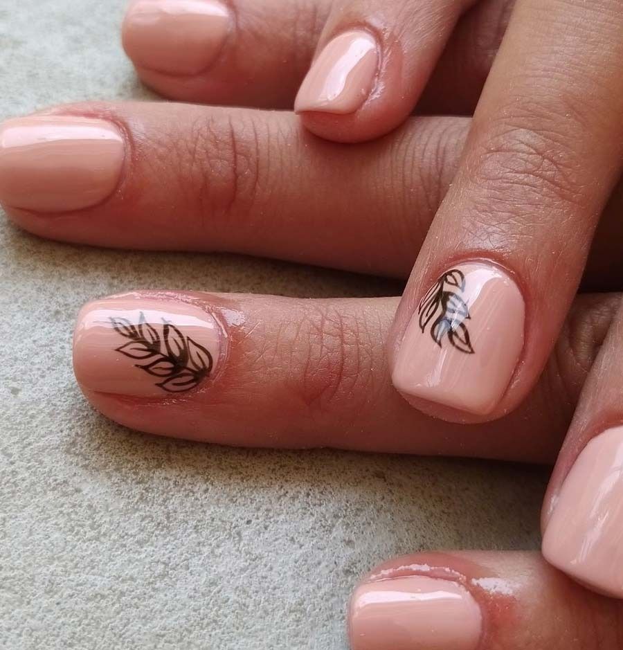 Un primer plano de las uñas de una mujer con un diseño de hojas.