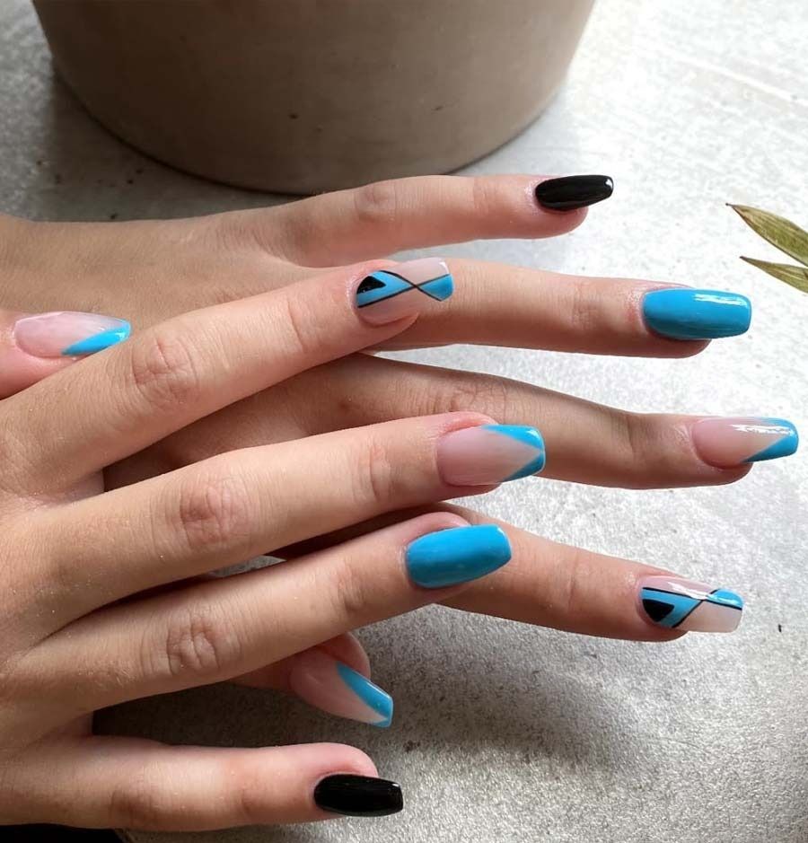 Un primer plano de las manos de una mujer con uñas azules y negras.