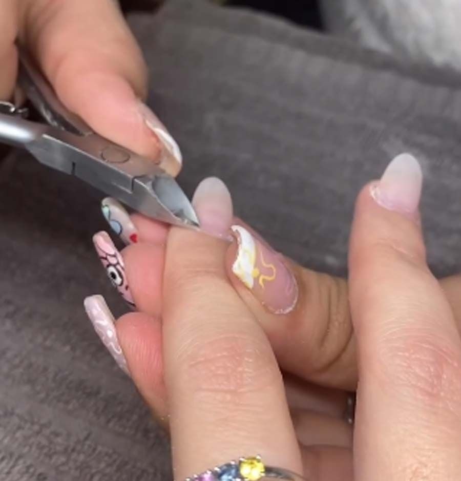 Una mujer se está haciendo las uñas con un par de tijeras.