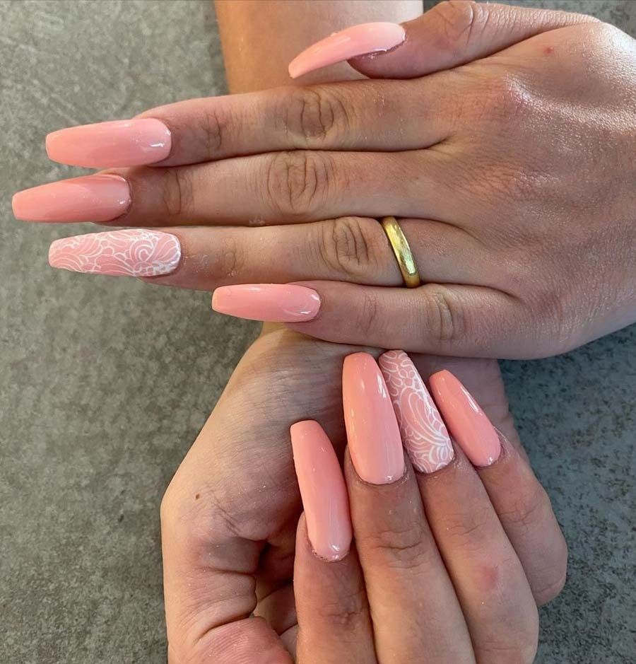 Manos de mujer con largas uñas rosadas y un anillo de oro.