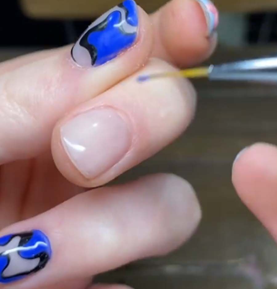 Una persona se pinta las uñas con un pincel.
