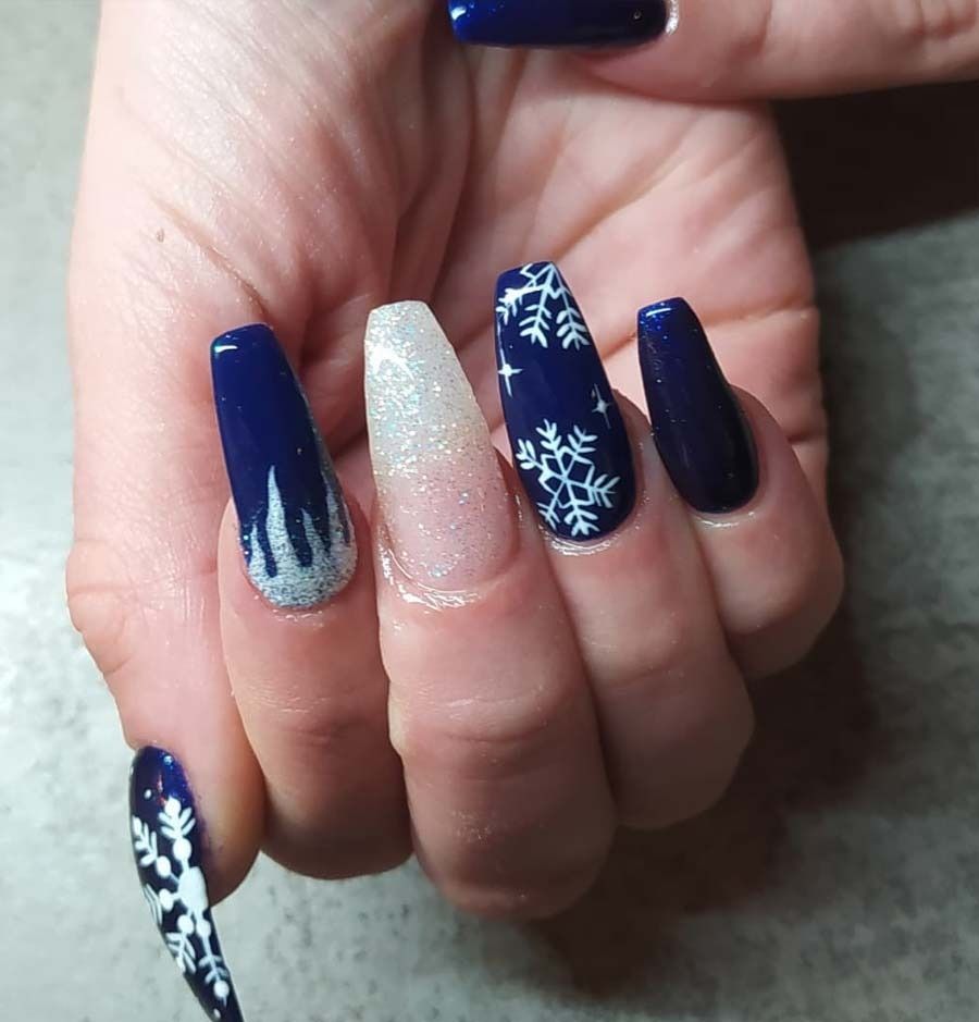 Un primer plano de las uñas de una persona con copos de nieve en ellas.