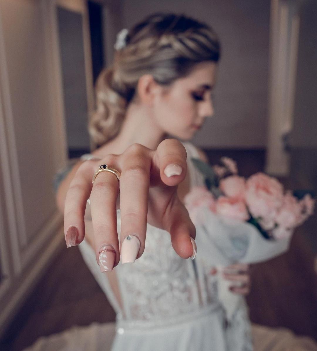 Una mujer con un vestido de novia sostiene un ramo de flores rosas.