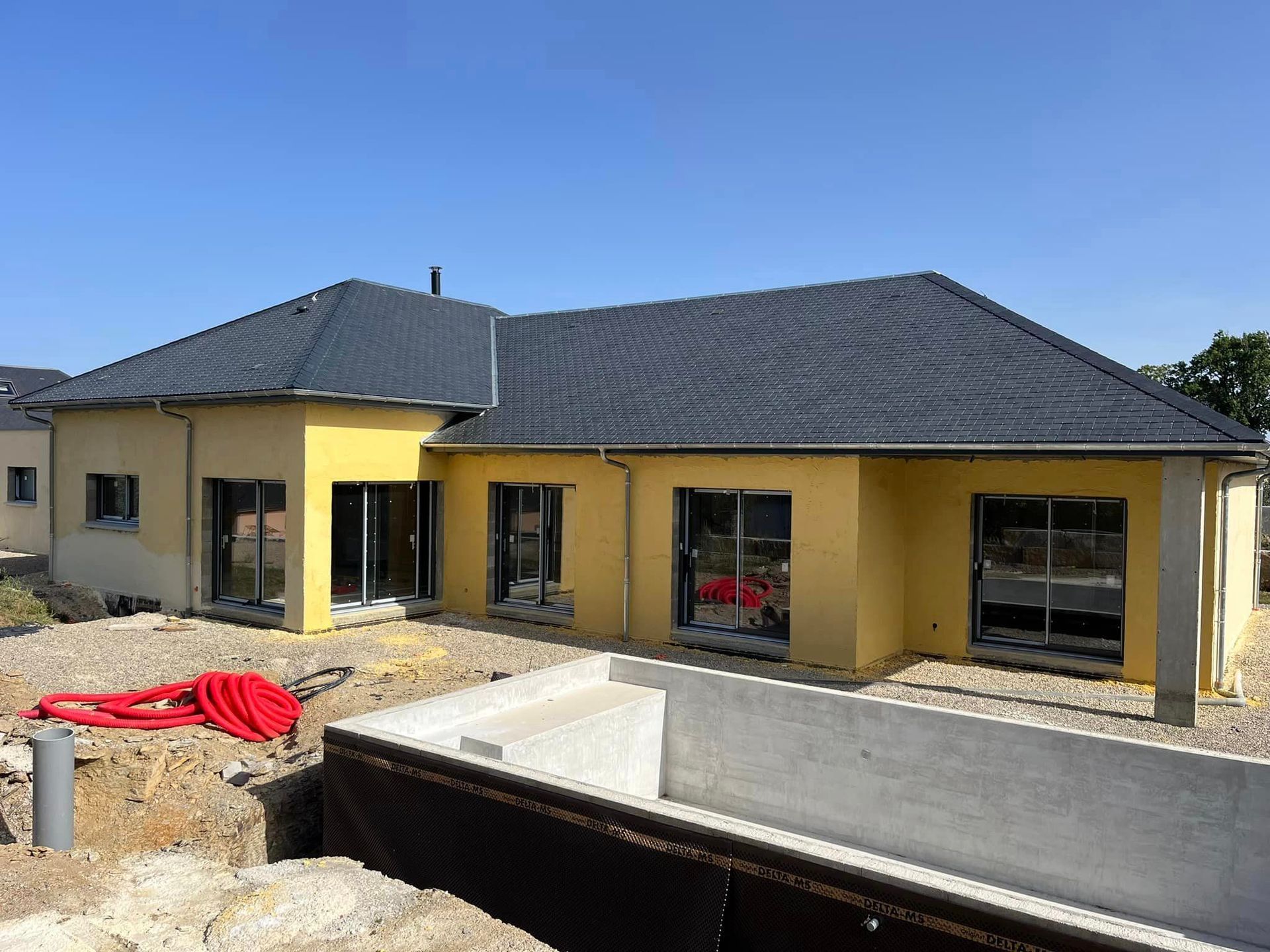 Maison jaune et piscine en construction