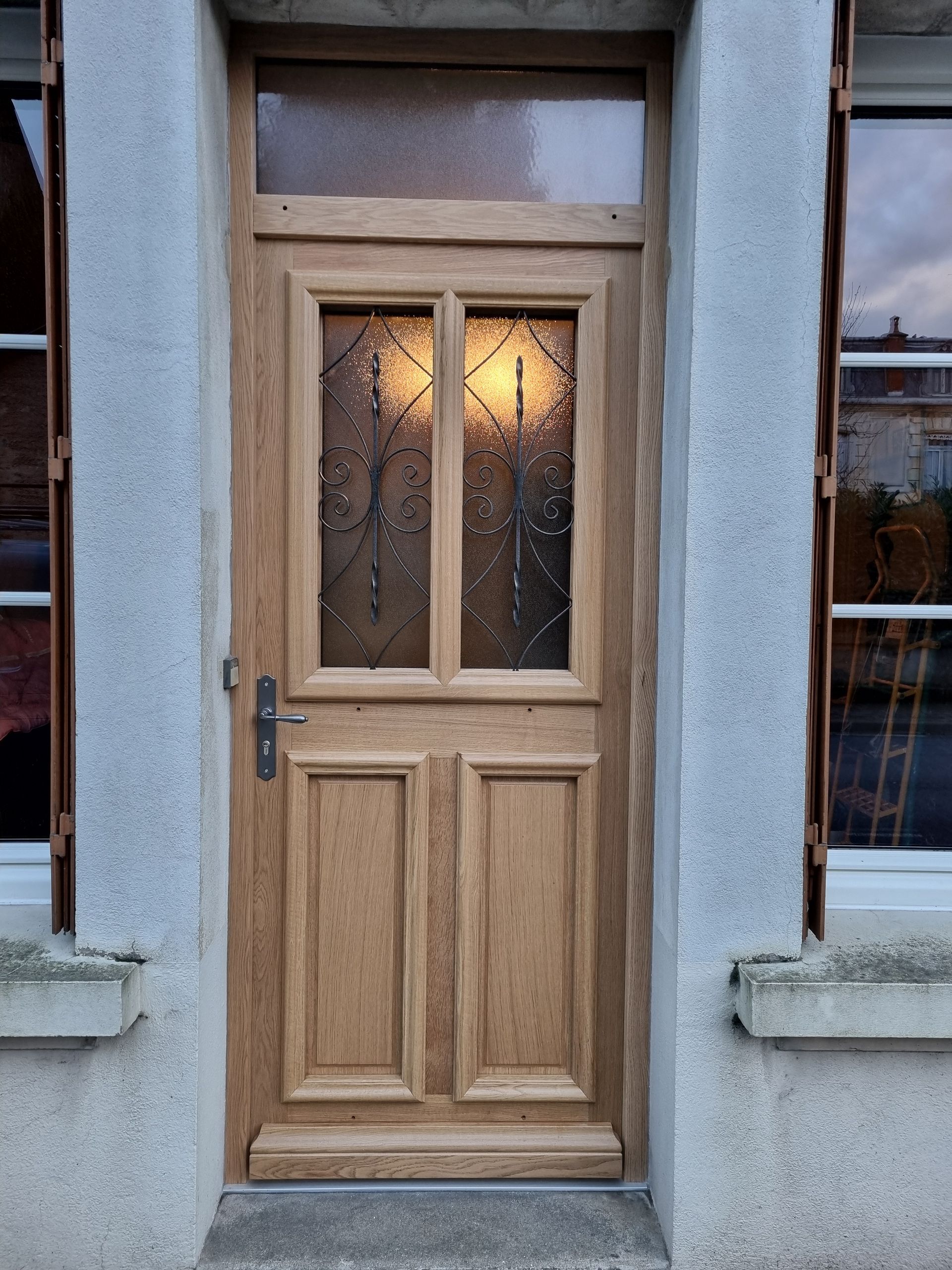 Porte d’entrée en bois avec des panneaux de verre dépoli.