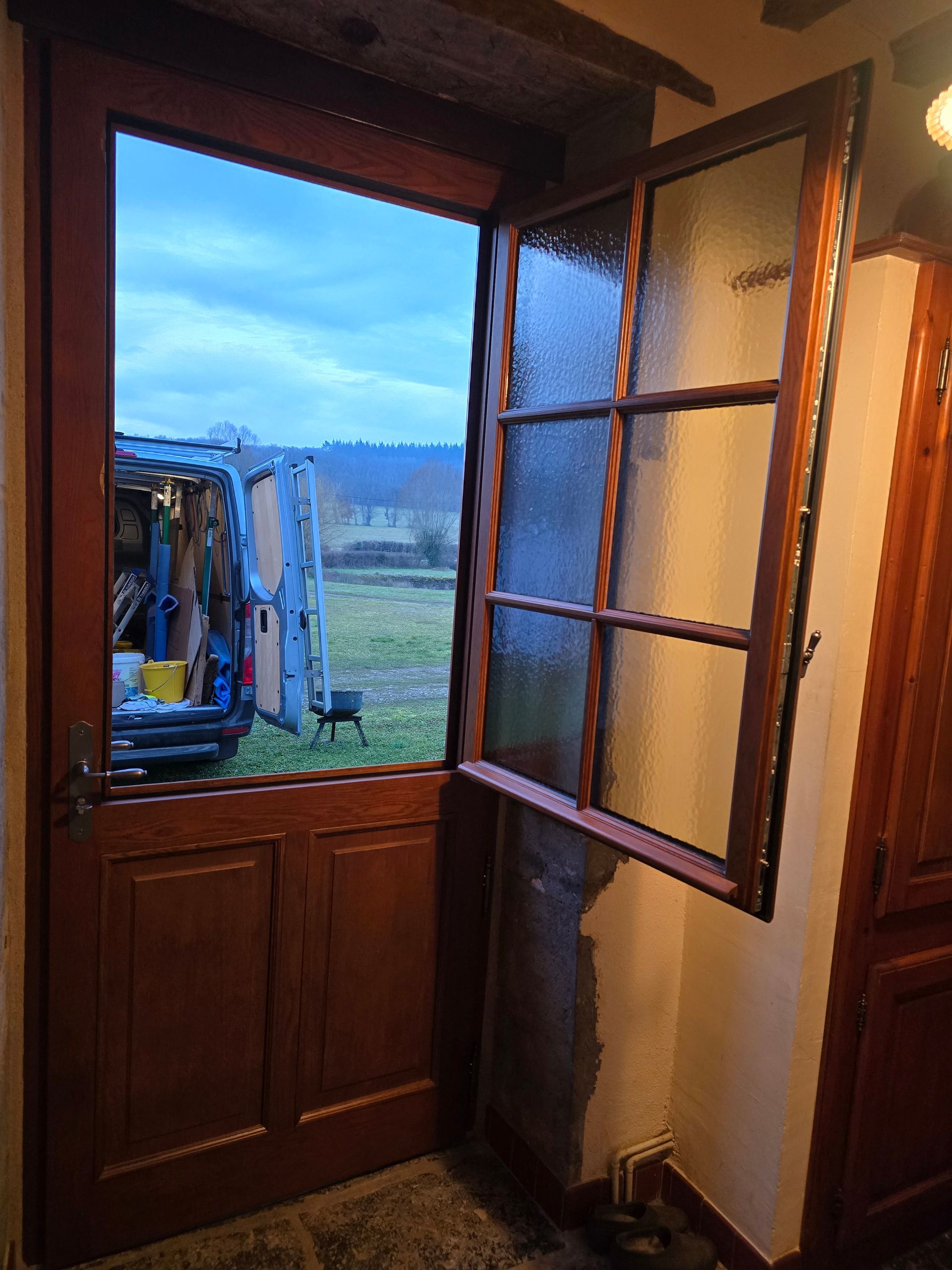 Porte et fenêtre en bois donnant sur un champ verdoyant.