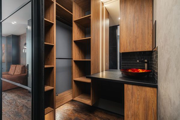 Dressing moderne avec rangements en bois, étagères ouvertes, plan de travail noir et coin coiffeuse éclairé