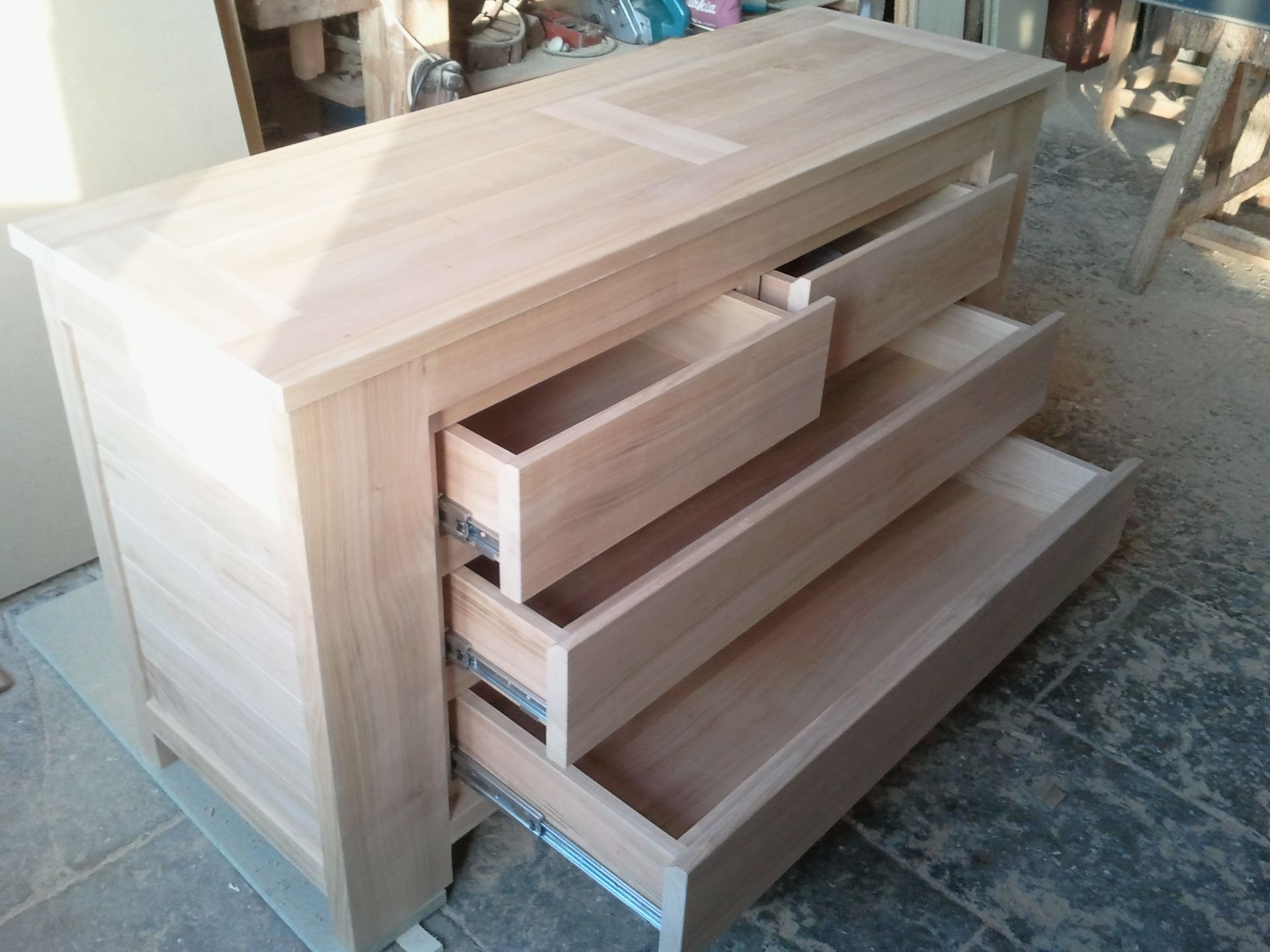 Commode en bois avec deux tiroirs ouverts dans un atelier ou un garage.