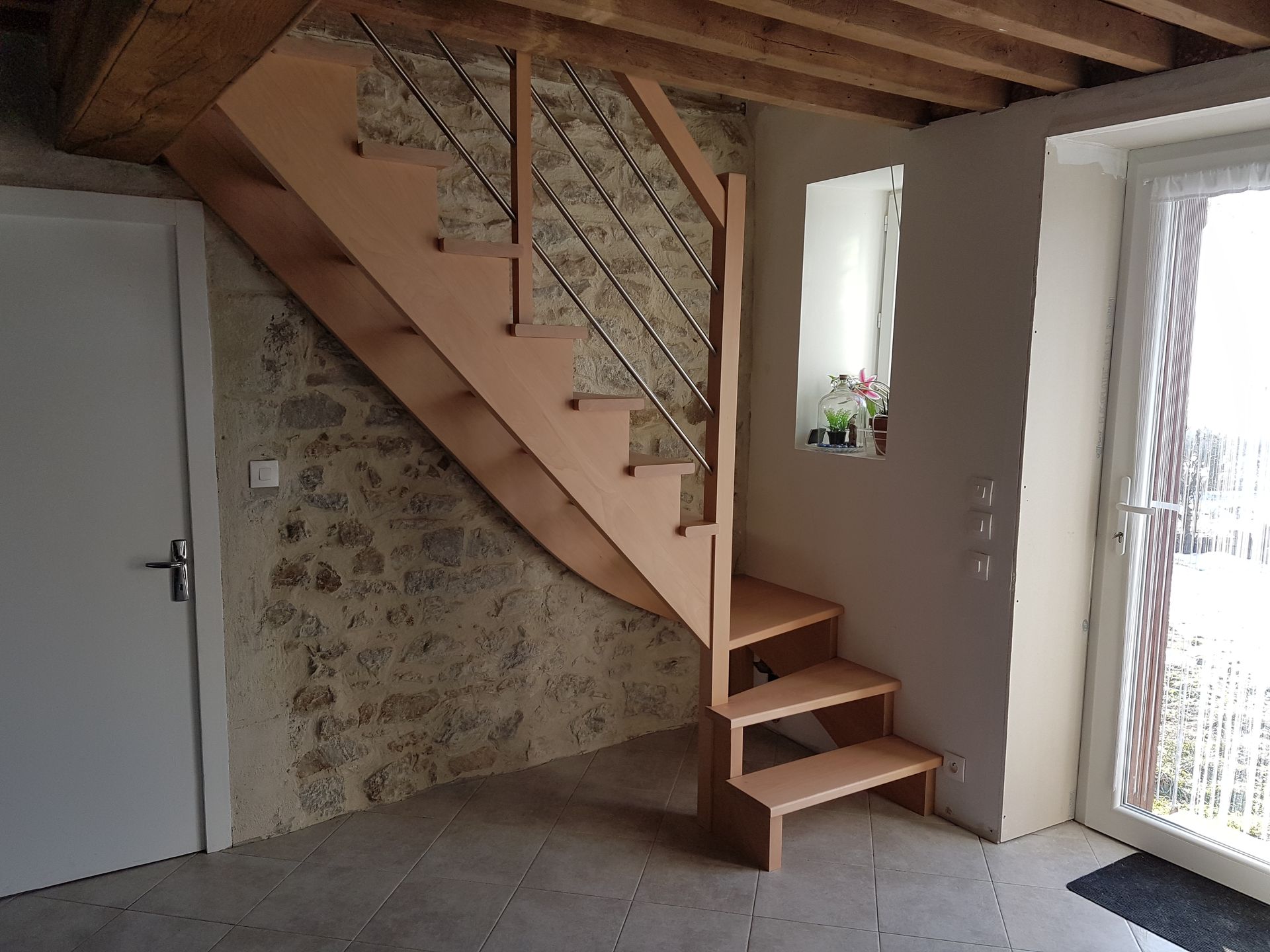 Escalier intérieur avec des marches en bois, un mur en pierre.