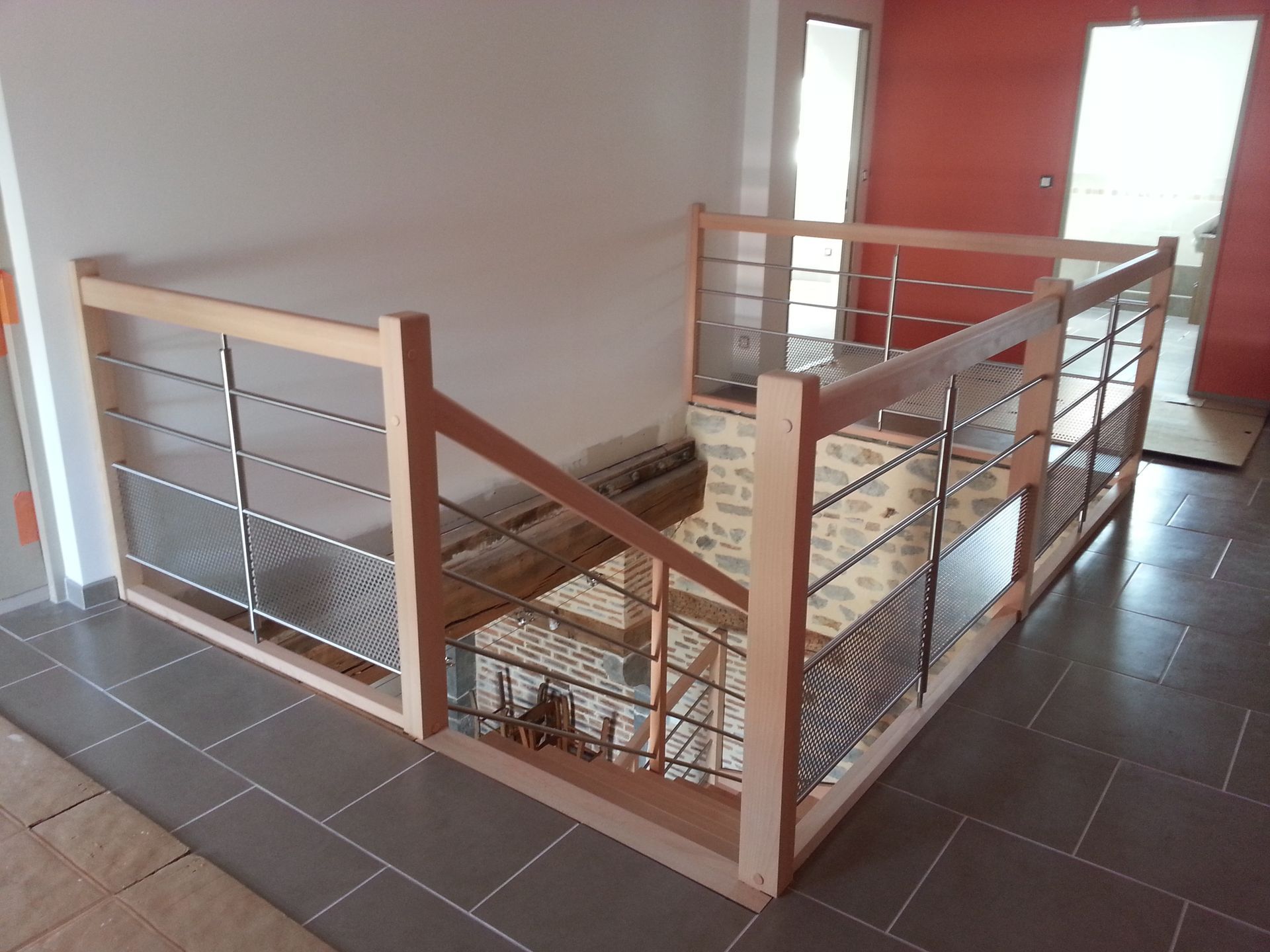 Palier d’escalier intérieur avec des rampes blanches et en bois et des câbles métalliques.