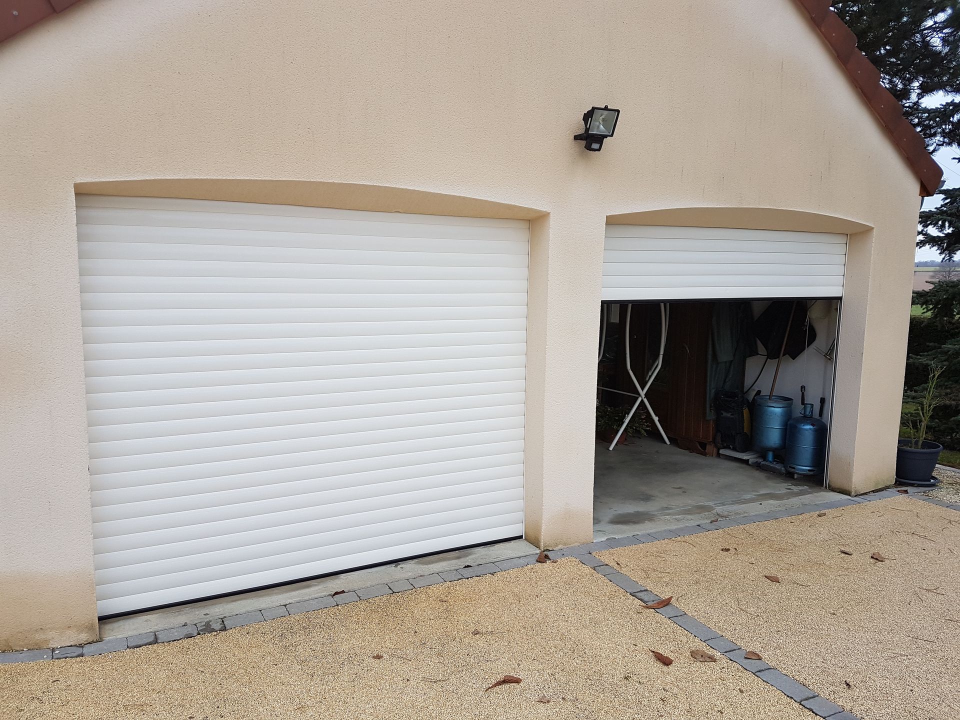 Extérieur d’une maison avec deux portes de garage blanches à enroulement.