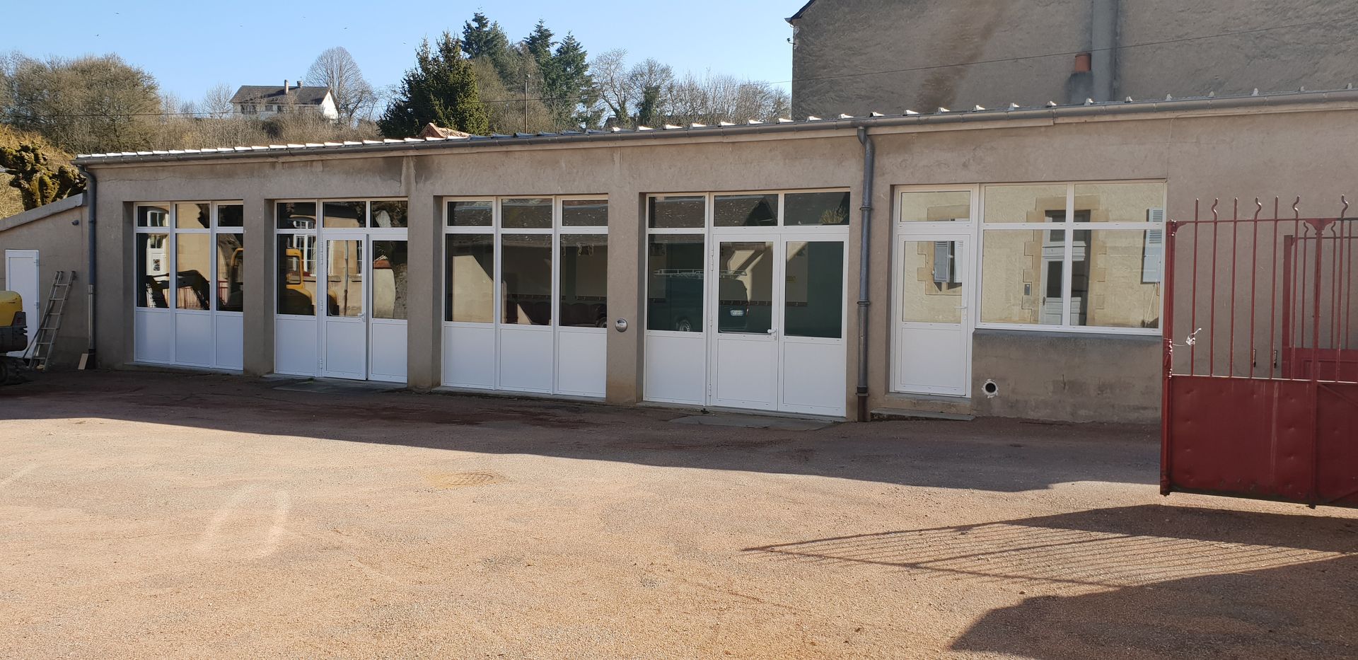 Bâtiment de plain-pied avec de nombreuses portes de garage vitrées.