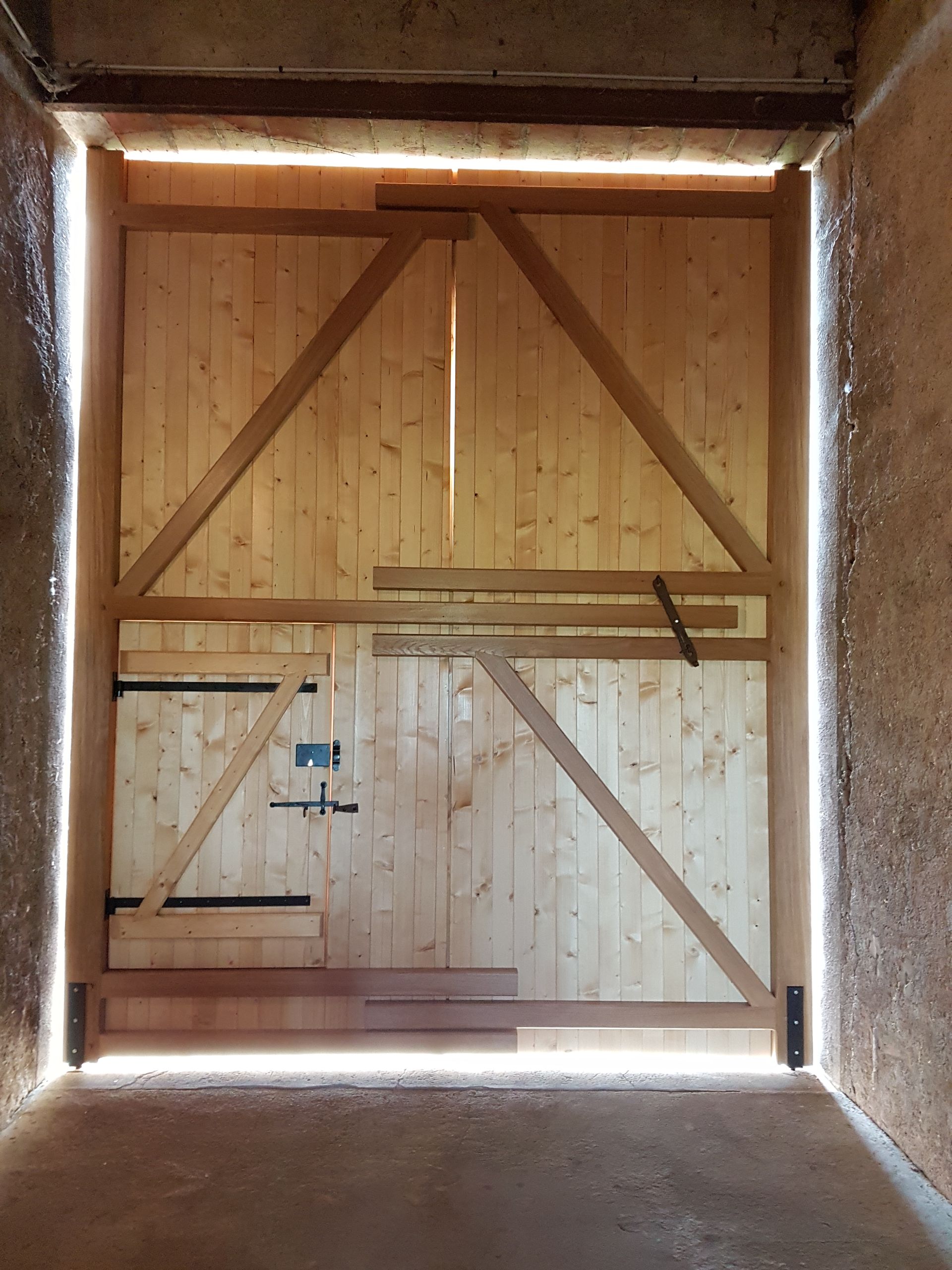 Porte de grange en bois avec des renforts diagonaux, vue depuis l’intérieur.