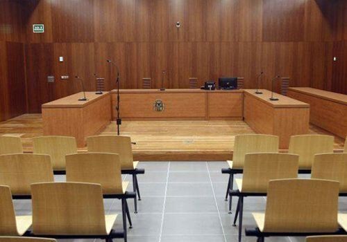 Una sala de audiencias vacía con mesas y sillas de madera