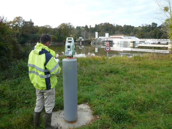 Un géomètre effectuant des mesure devant la Moselle