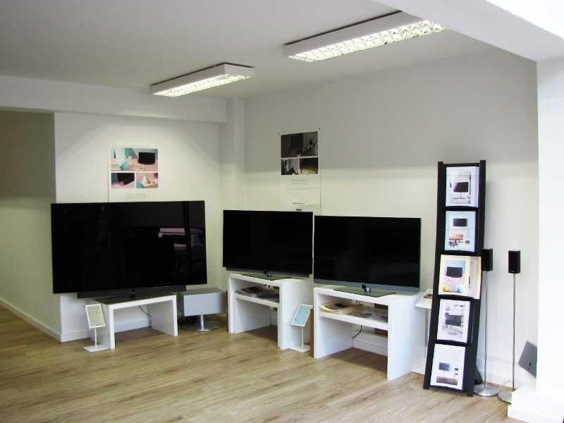 Ein Wohnzimmer mit zwei Flachbildfernsehern und einem Zeitschriftenständer
