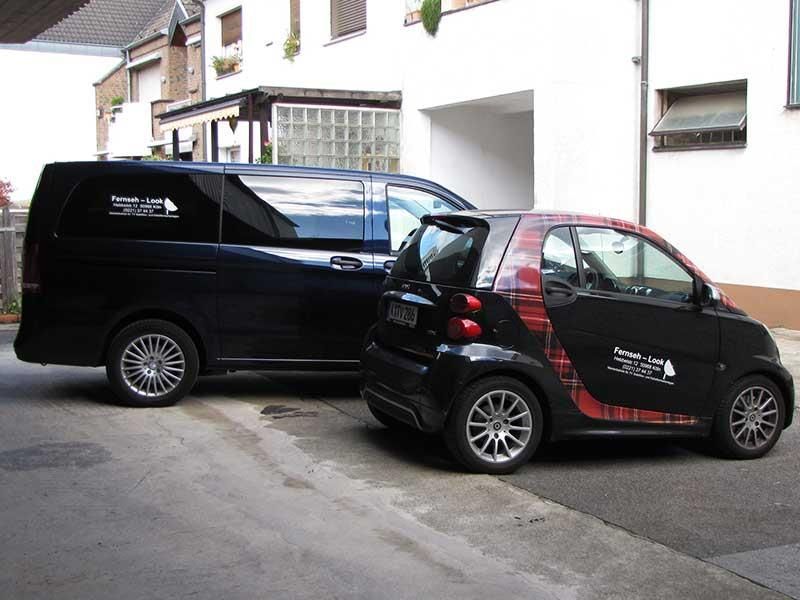 Ein Smart ist neben einem schwarzen Van geparkt