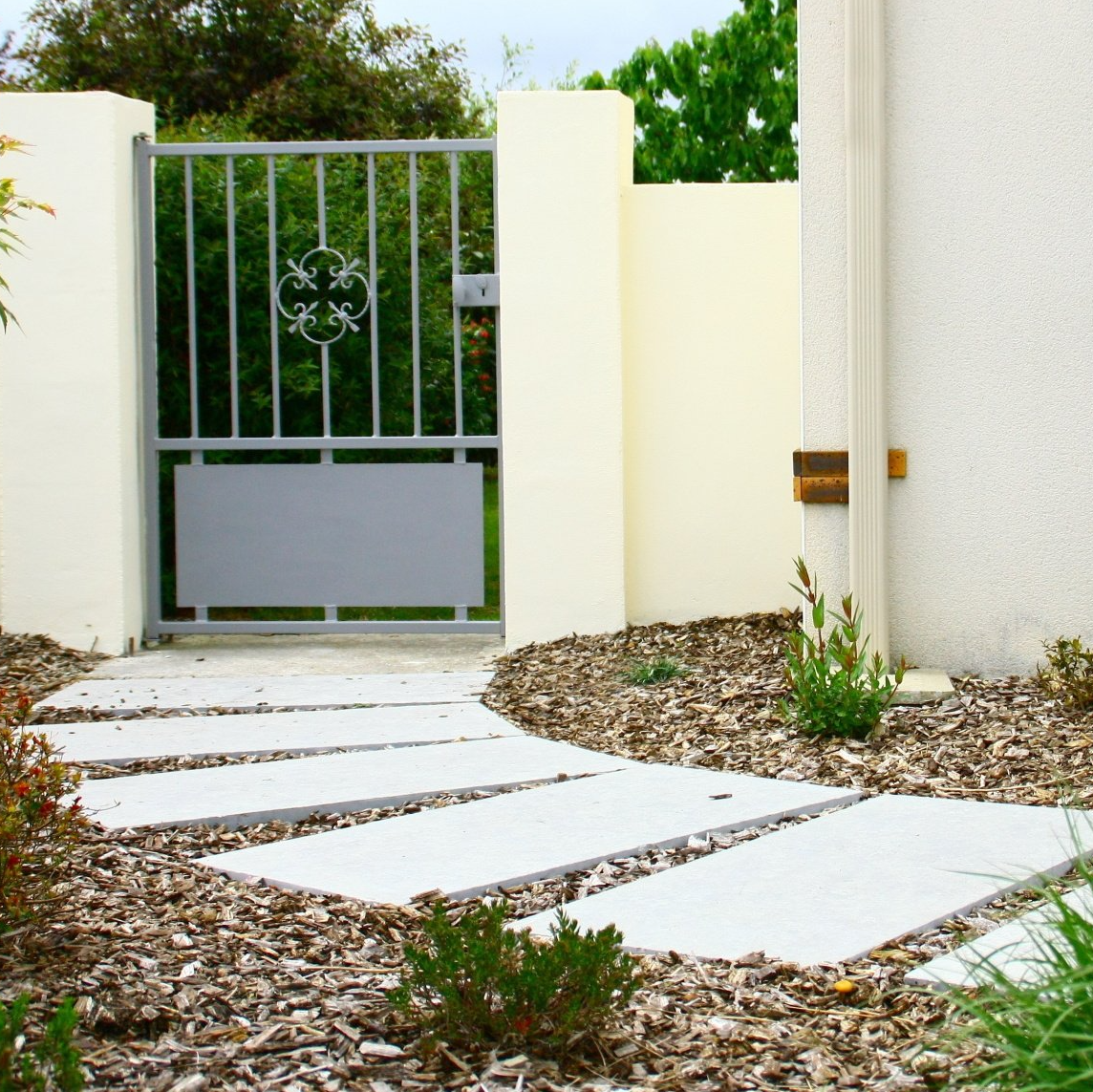 Un aménagement d'extérieur, avec un sentier en pierre et un muret en crépi
