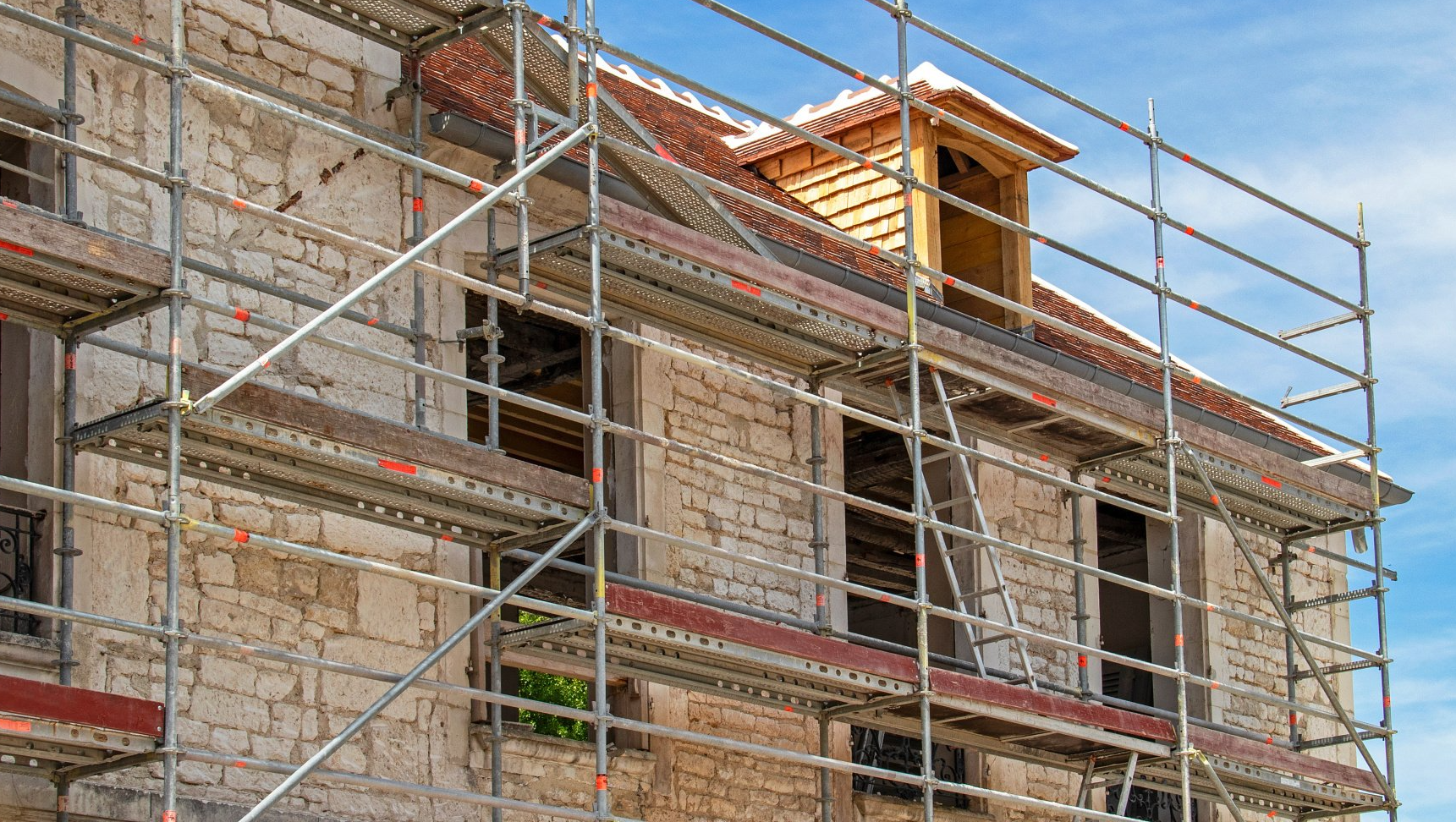 Un échafaudage posé contre une façade en moellon d'une maison ancienne