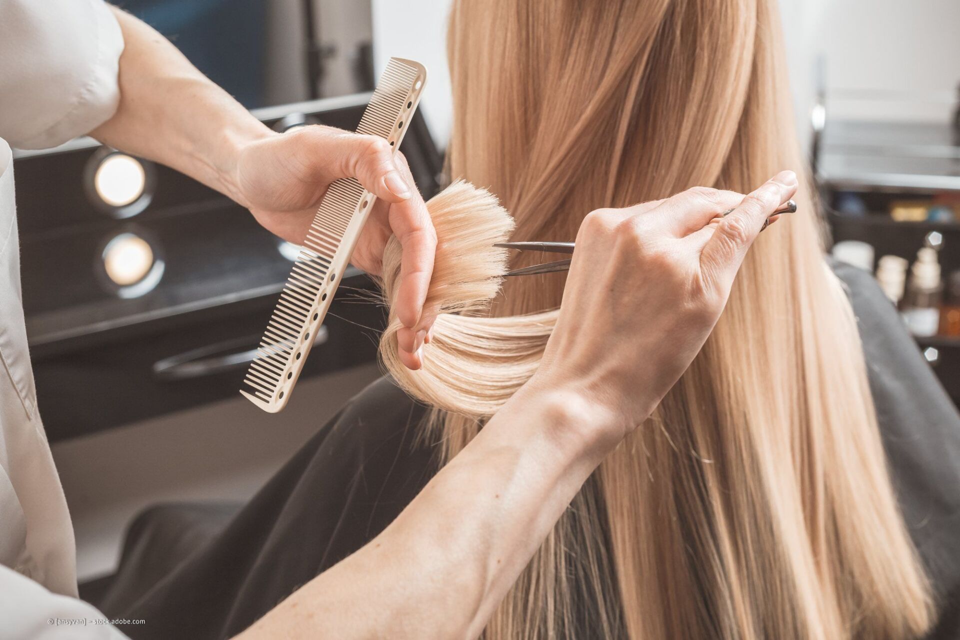 Friseur schneidet Frau mit langen blonden Haaren die Spitzen