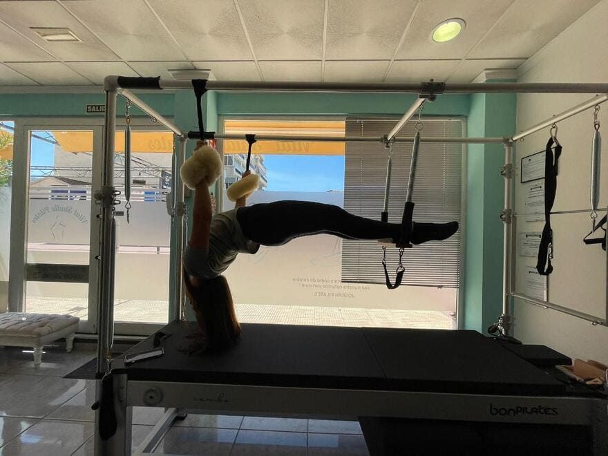 Una mujer está haciendo ejercicios en una máquina de pilates en un gimnasio.