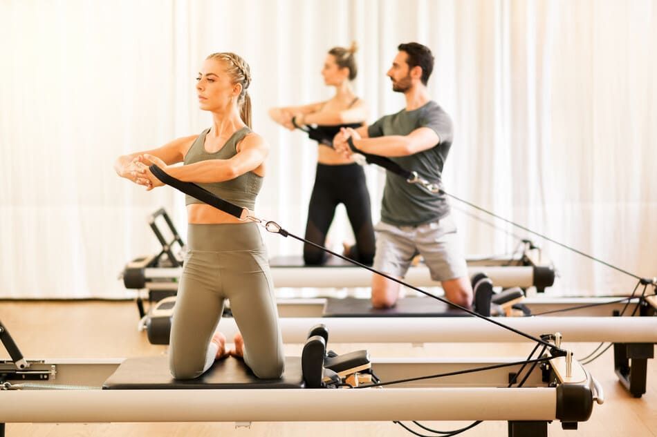 Un grupo de personas está haciendo pilates en una máquina de pilates en un gimnasio.