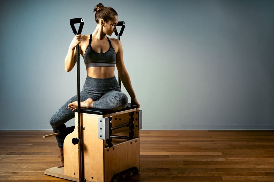 Una mujer está sentada en una máquina de pilates.