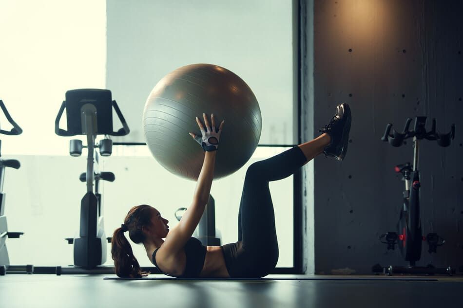 Una mujer está haciendo ejercicios con una pelota de ejercicios en un gimnasio.
