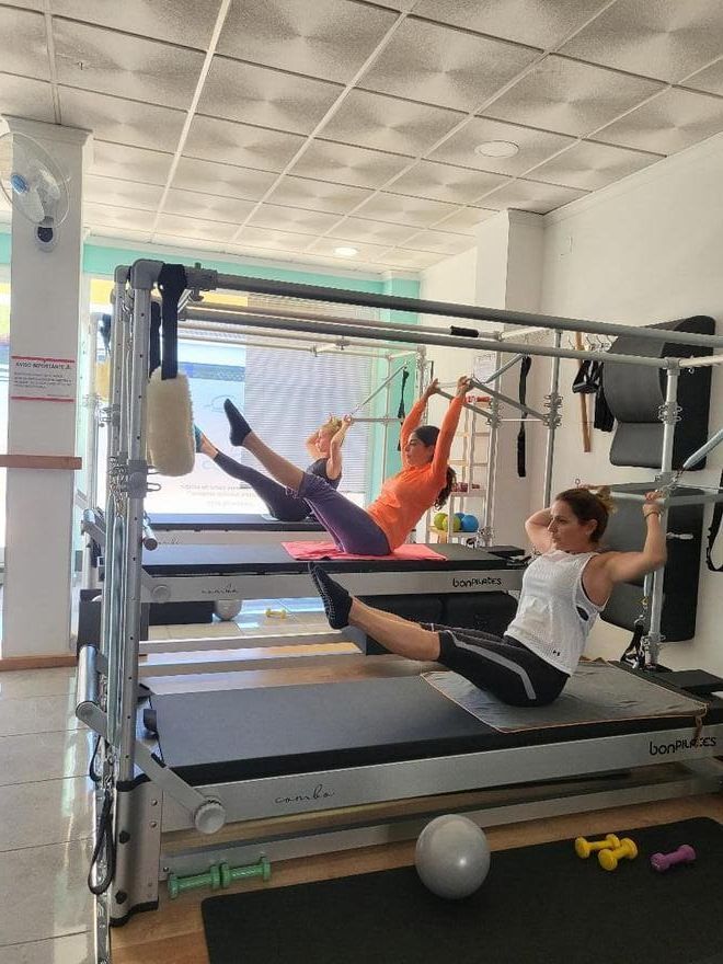 Un grupo de personas está haciendo ejercicios en una máquina de pilates en un gimnasio.
