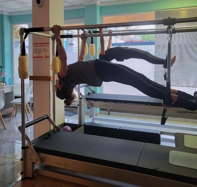Dos personas están haciendo ejercicios en una máquina de pilates.