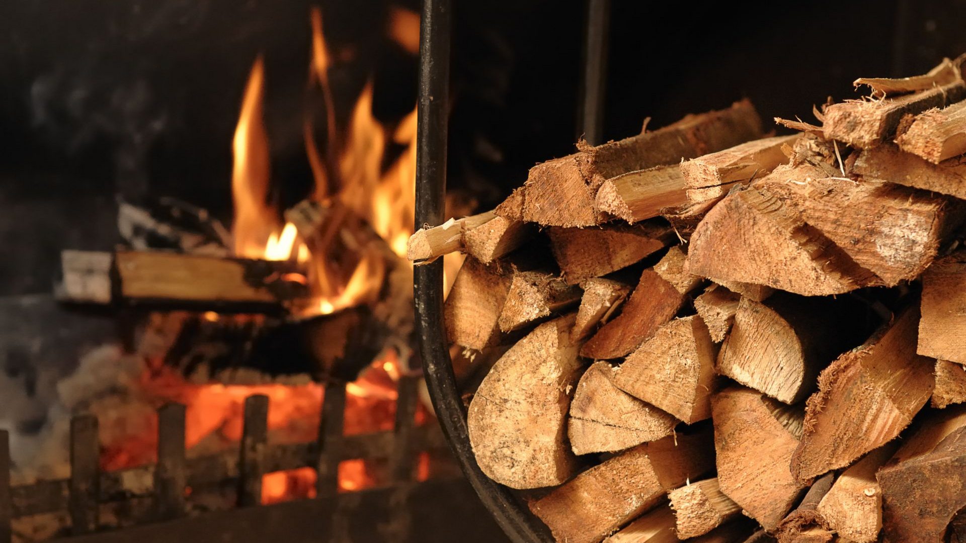 Cheminée avec des bûches brûlantes, à côté d'un panier rempli de bois de chauffage