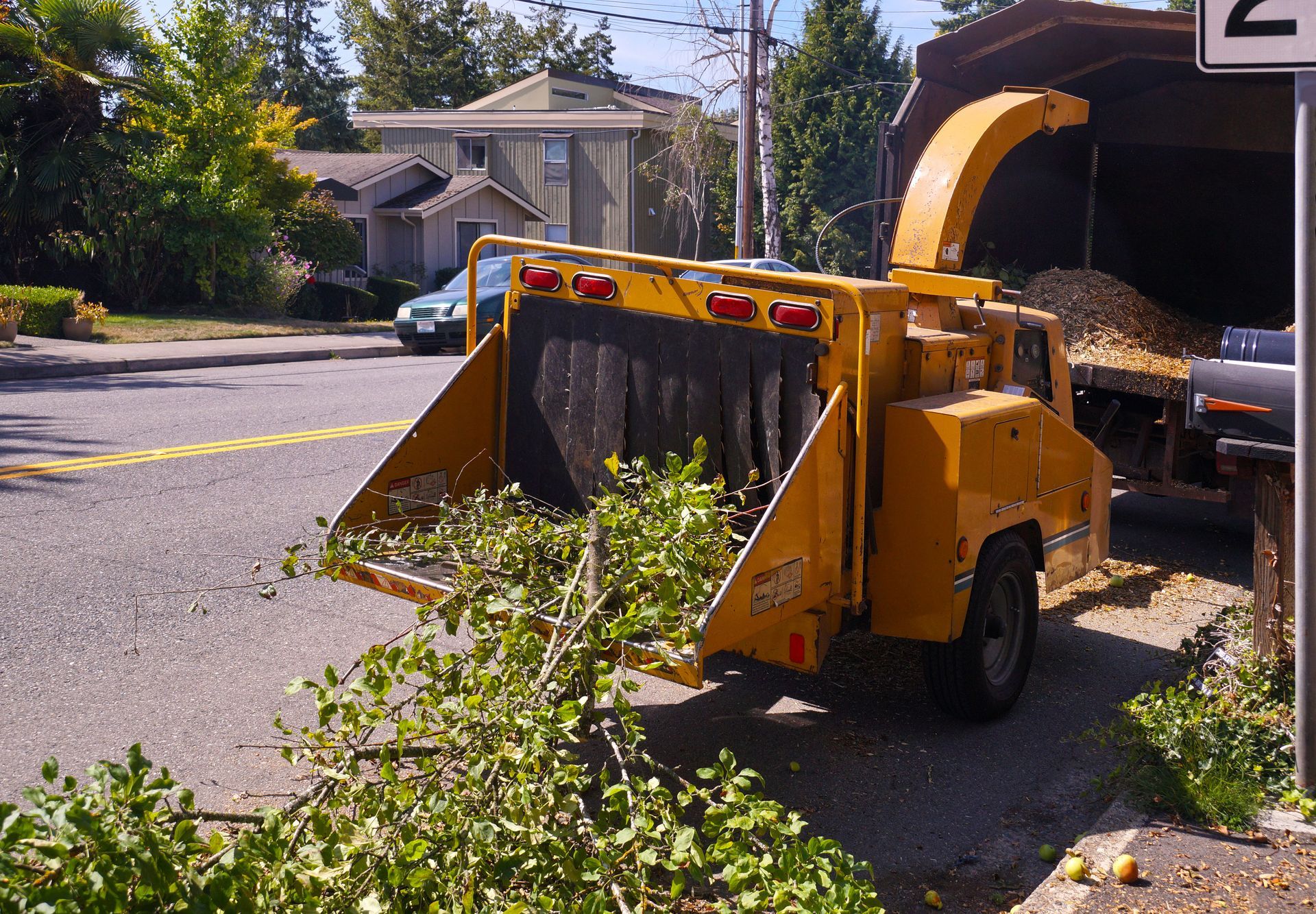 Broyeur à bois jaune dans une rue, traitant les branches et les alimentant dans un camion