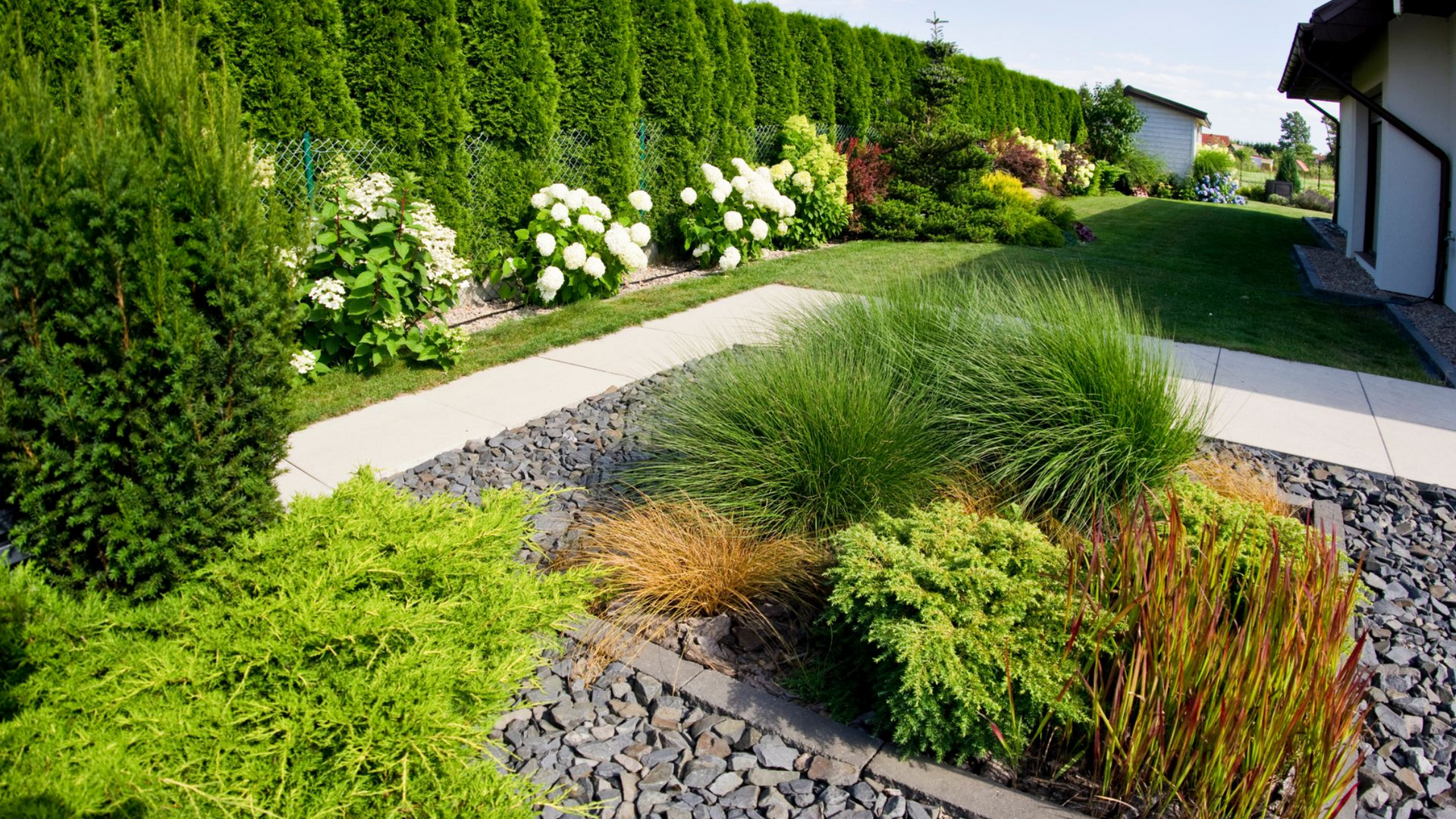 Jardin paysager avec verdure luxuriante, chemin en pierre et fleurs
