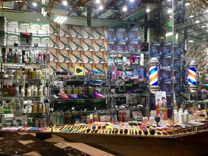 Una barbería llena de productos y una pared con espejos.