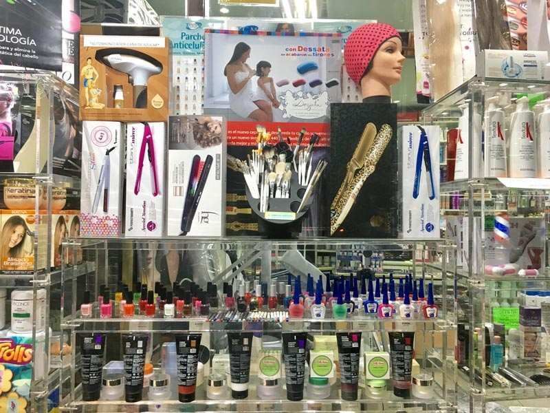 Un estante de una tienda lleno de muchos cosméticos y una cabeza de maniquí.