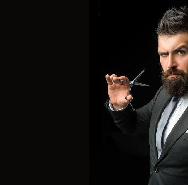 Un hombre con traje y corbata sostiene un par de tijeras en su mano.