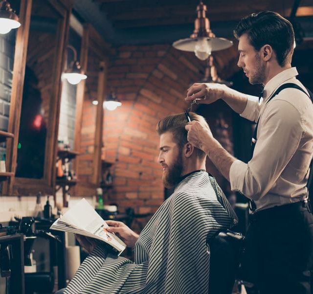 Un hombre se está cortando el pelo con un barbero en una barbería.